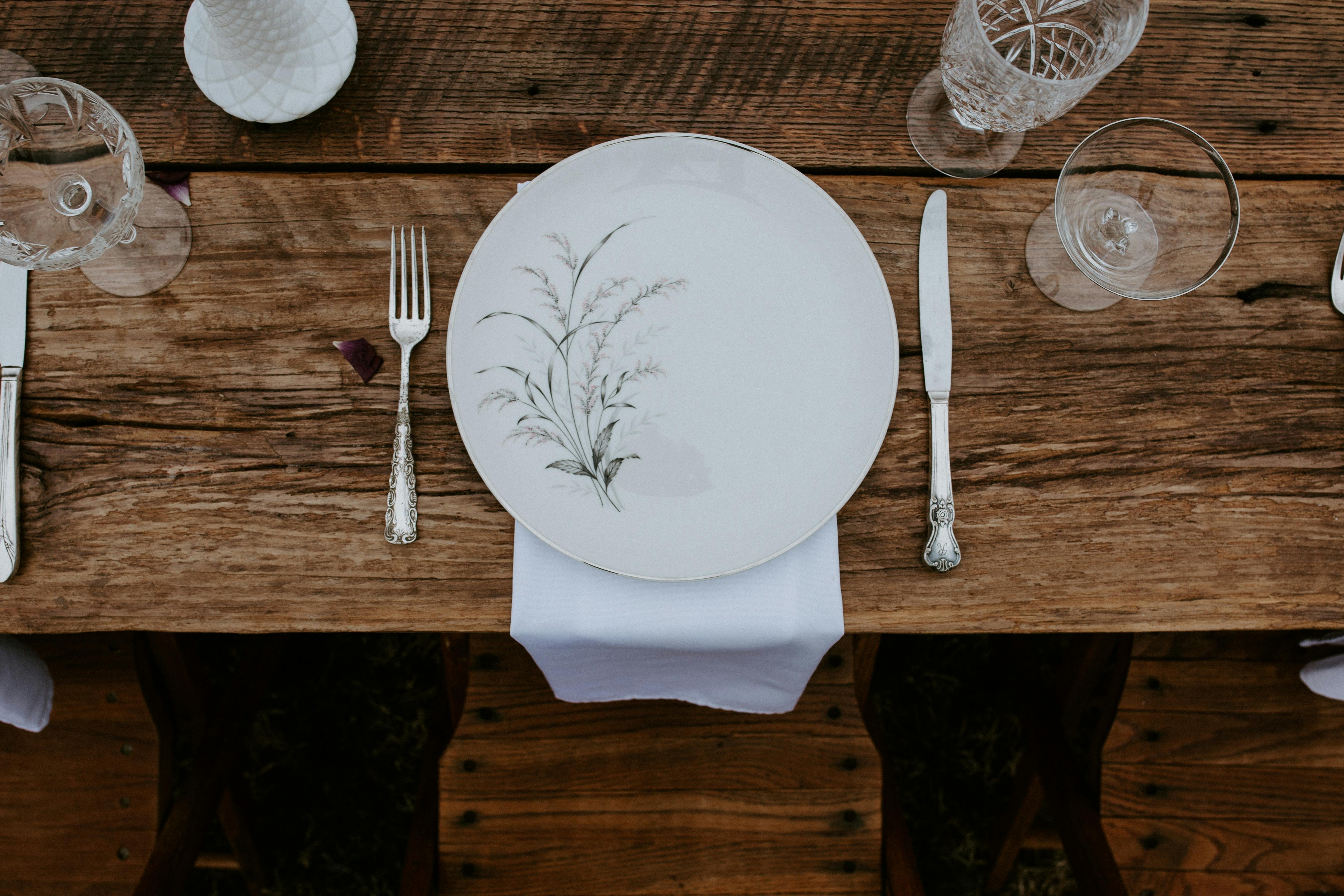Elegant rustic table setting with vintage cutlery and floral dinnerware.