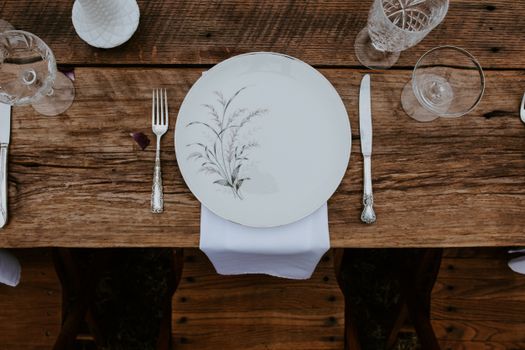Elegant rustic table setting with vintage cutlery and floral dinnerware.