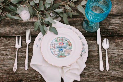 White and Blue Floral Ceramic Plate Beside Fork and Bread Knife on White Table Cloth