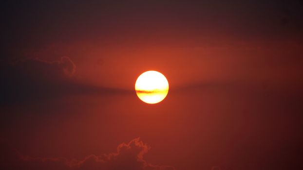 Captivating view of the sun setting with a vivid red sky and clouds in India.