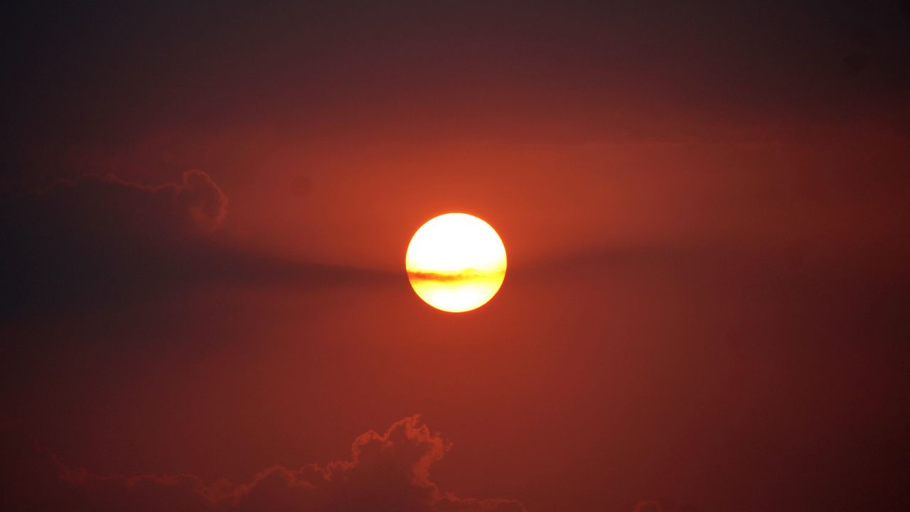 captivating view of the sun setting with a vivid red sky and clouds in