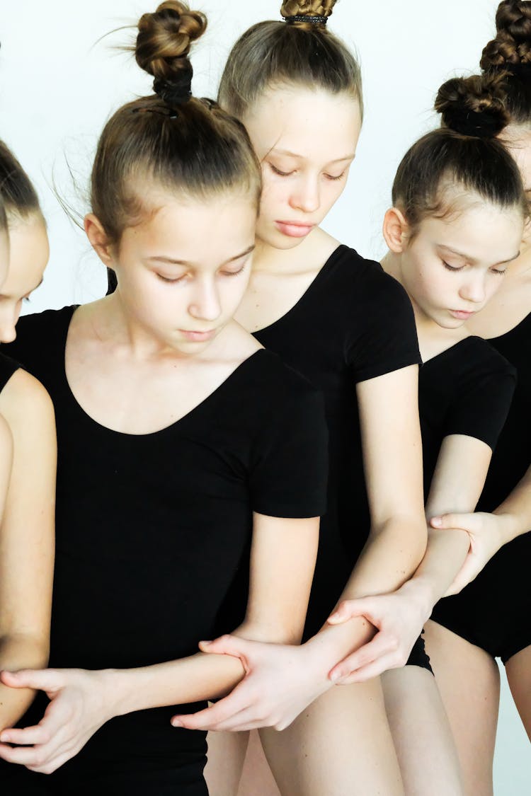 A Group Of Young Girls In Black Clothes Holding Each Others Arms