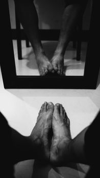 Black and white photo of bare feet reflected in a mirror, creating an abstract visual.