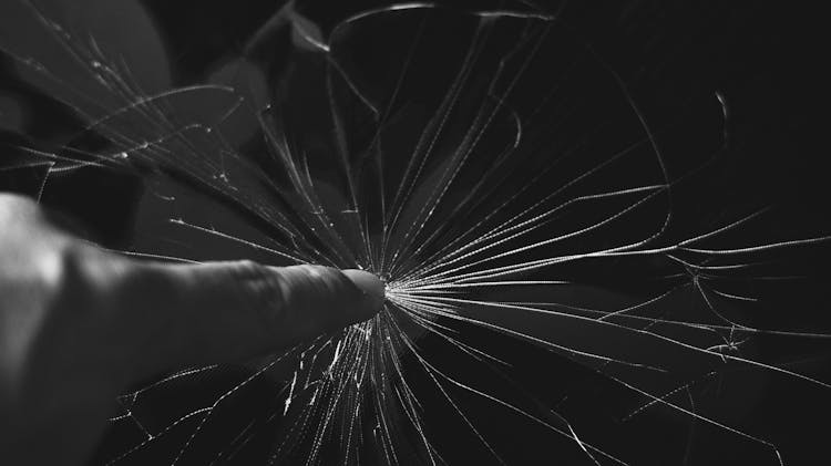 Black And White Photo Of Finger Touching Cracked Glass 