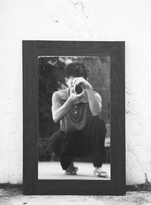 Man Taking Photo of a Wooden Framed Mirror