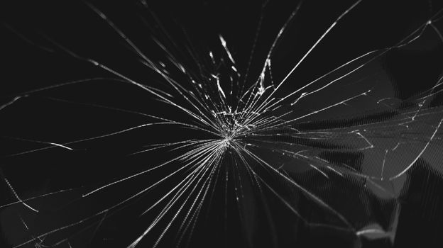 Close-up shot of shattered glass in monochrome, creating an abstract pattern.