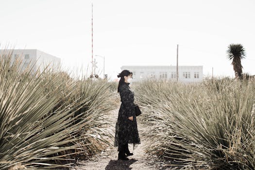 A woman in a mask and long dress stands in a desert landscape near Marfa, Texas.
