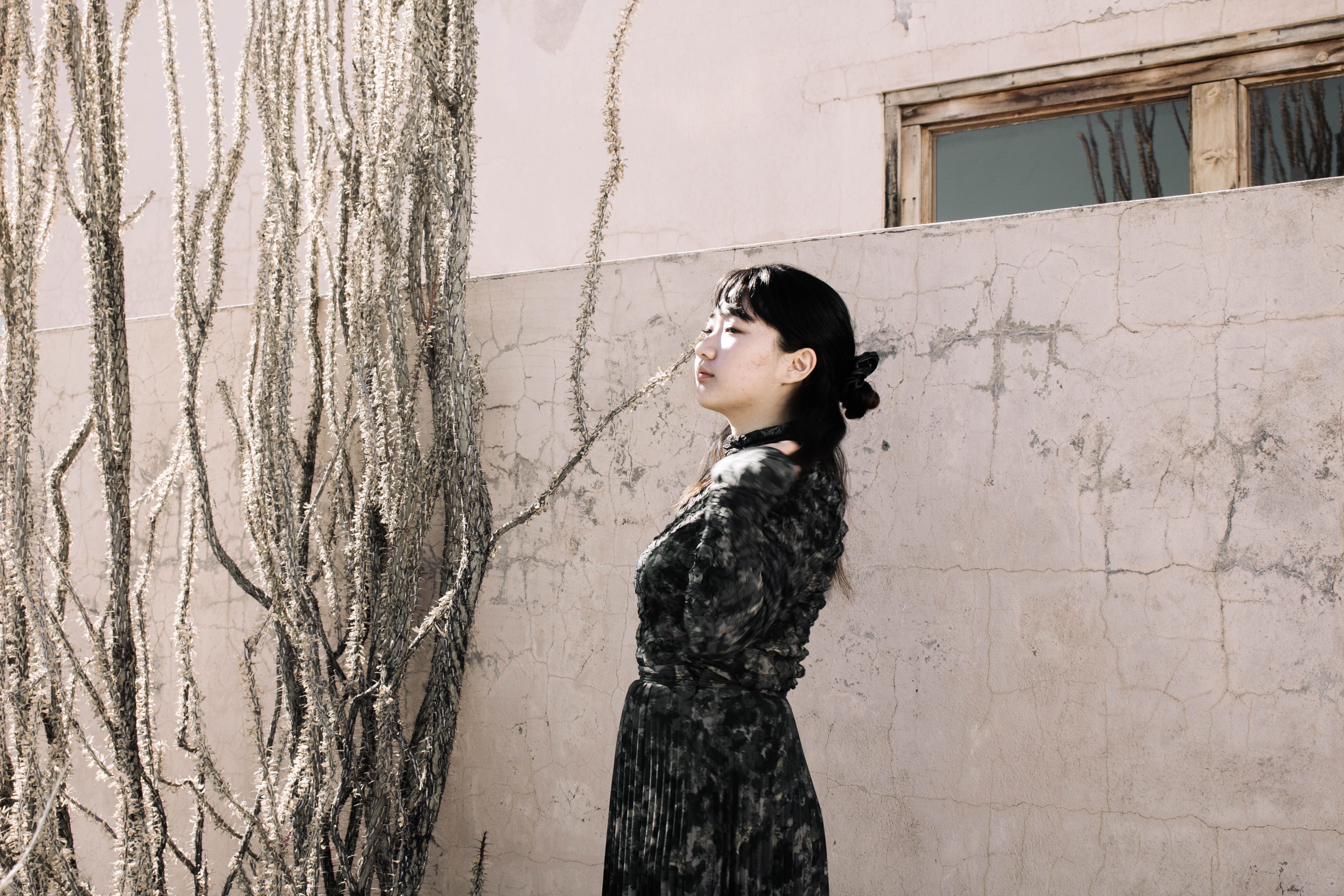 Woman in Black Dress Standing Beside a Wall · Free Stock Photo