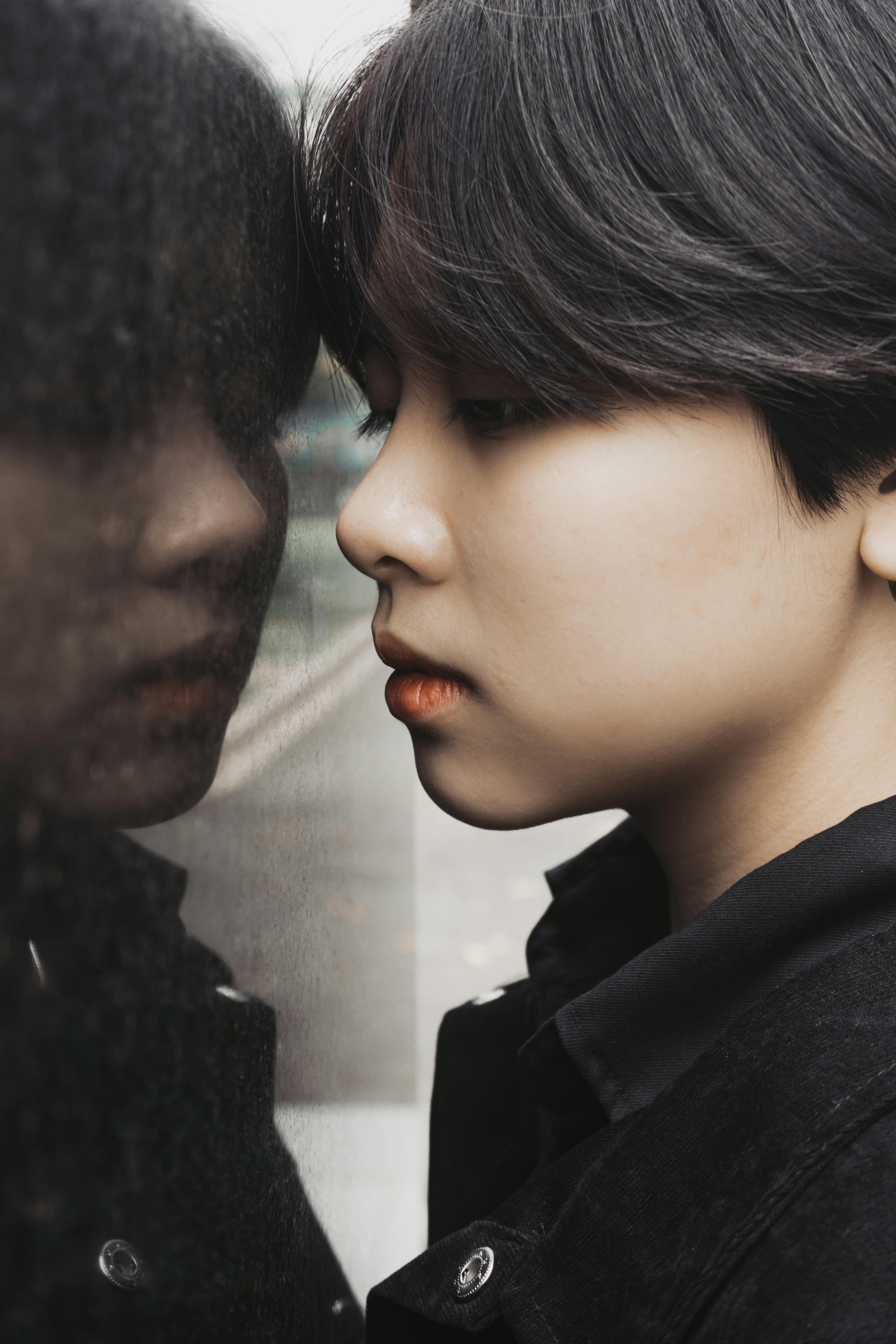 Close-up of a young woman gazing at her reflection in a window.