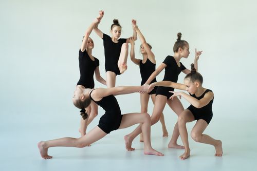 Free A group of young girls performing dance poses in black bodysuits on a white background. Stock Photo