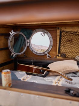 A warm van interior showing a guitar, cup, and a scenic desert view through a circular window.