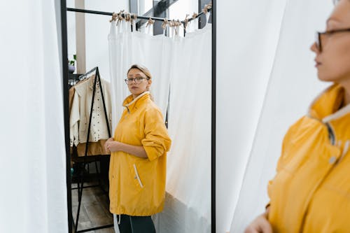 Free Woman in Yellow Jacket Standing in Front of a Mirror Stock Photo