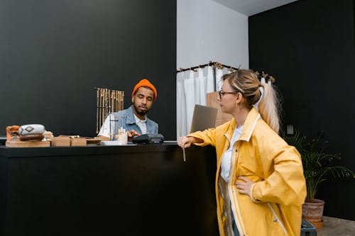 Free Woman in Yellow Jacket Standing in Front of a Cashier Stock Photo