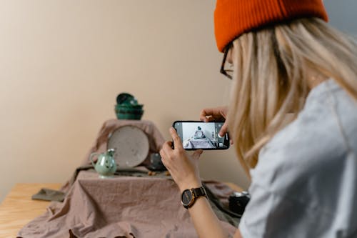 Free Woman in Orange Knit Cap Taking Photos of Tableware Stock Photo