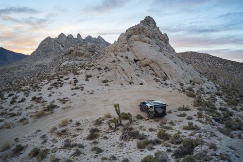 Free A rugged desert landscape featuring a camper truck near rock formations at dusk in Inyokern, CA. Stock Photo
