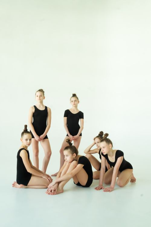 Free Group of children ballet dancers in black leotards posing for a rehearsal indoors. Stock Photo