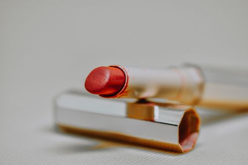 Free Sophisticated close-up shot of a red lipstick with reflective case on a neutral background, highlighting beauty and elegance. Stock Photo