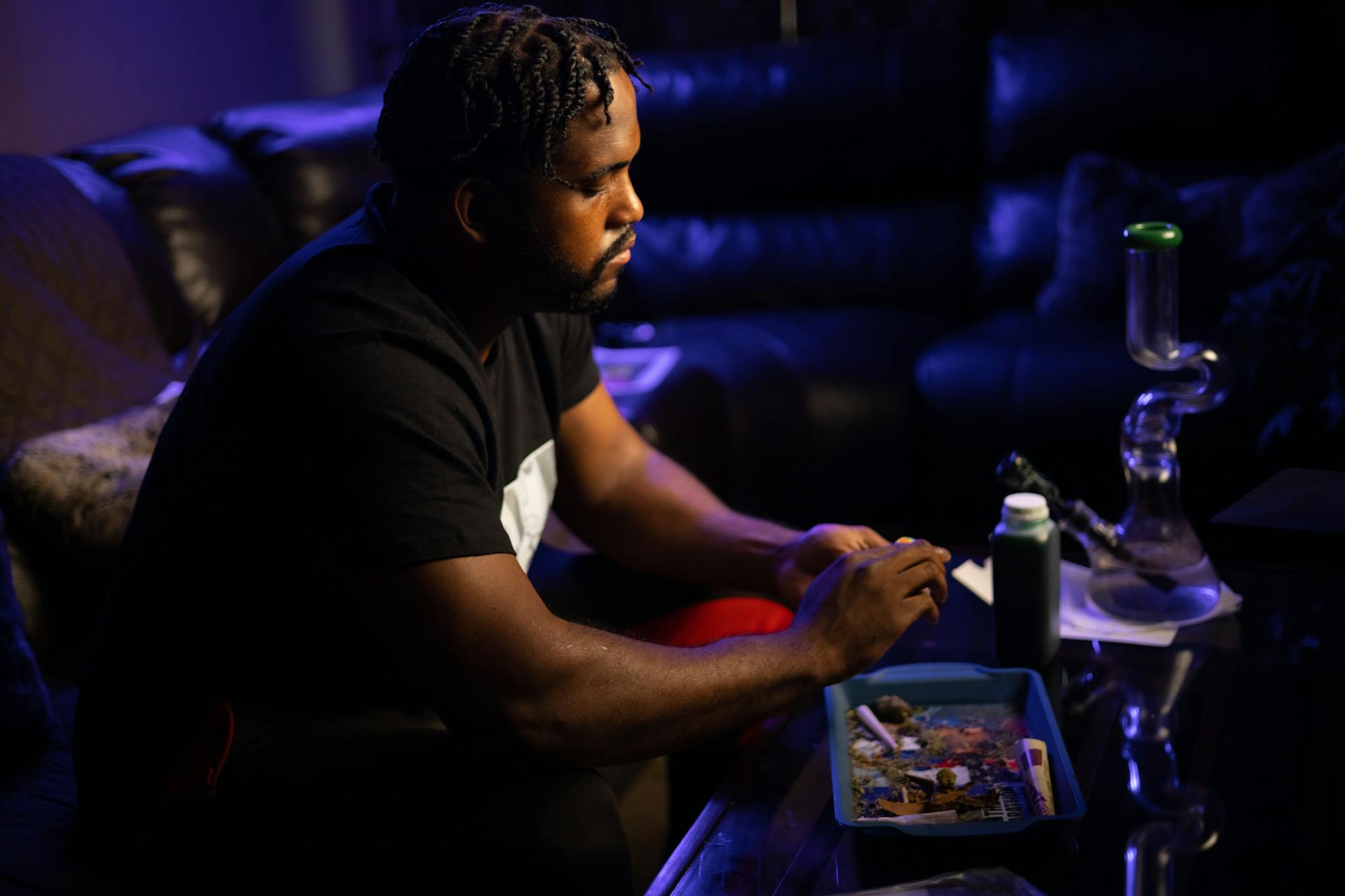 A man engages with cannabis accessories in a relaxed indoor setting.