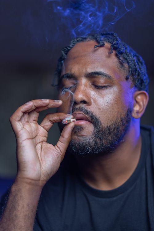 Free Close-up portrait of a man smoking, surrounded by smoke in a calm atmosphere. Stock Photo