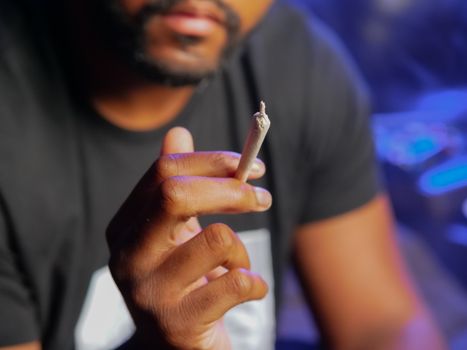A person holds a cannabis joint in hand, showcasing cannabis culture in an intimate setting.