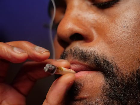 A close-up of a person inhaling a cannabis joint, highlighting smoke and texture.