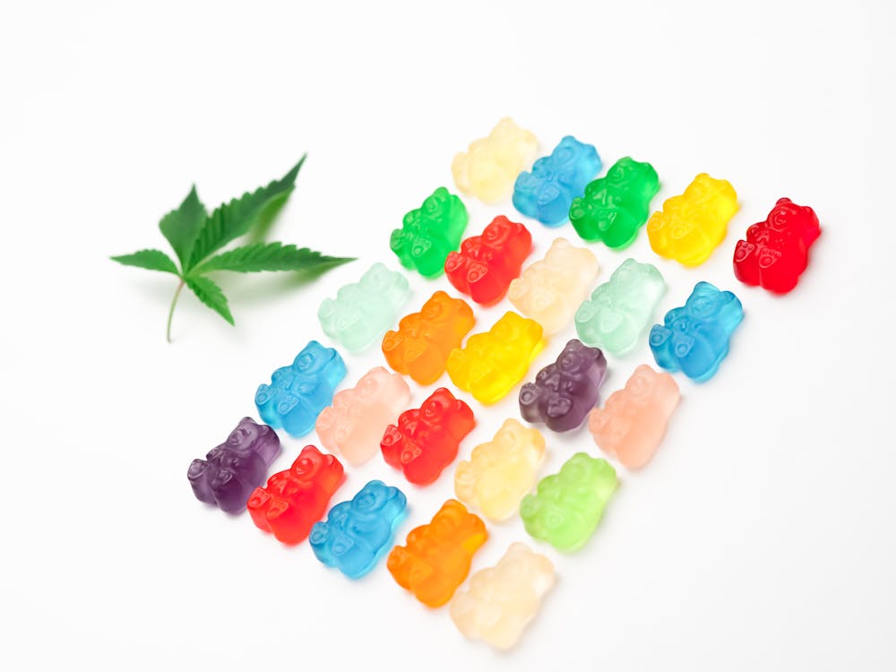 Free Vibrant assorted gummy bears arranged with a cannabis leaf on a white background. Stock Photo
