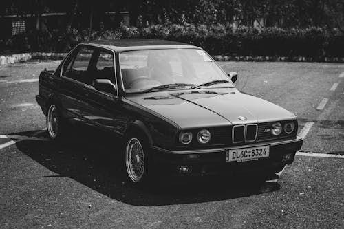 Grayscale Photo of a Vintage Car Parked on the Road