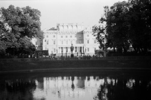 Free Black and white photo of an elegant mansion reflecting in a pond, framed by trees. Stock Photo