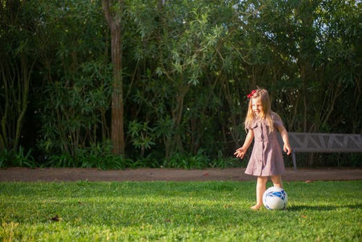A cheerful young girl playing with a soccer ball on a sunny day in a Portuguese park.