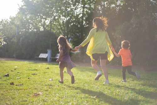 Free A mother with two children running and playing in a sunny park, enjoying family time. Stock Photo