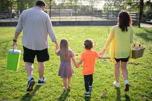 A Family Walking on a Grassy Field