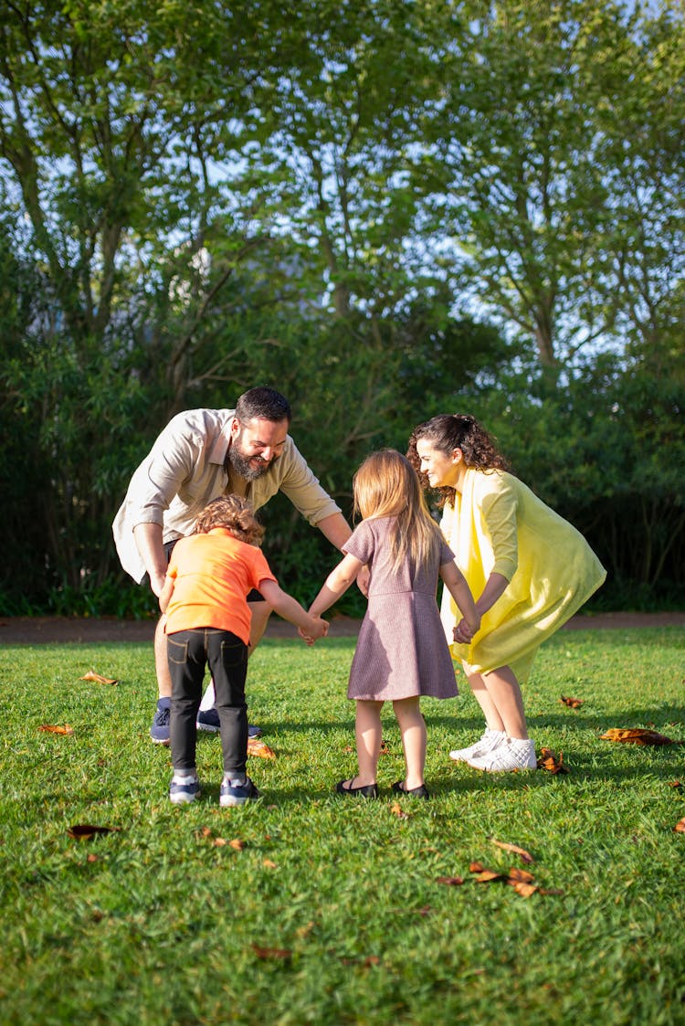 A Family Playing On The Green Grass Field