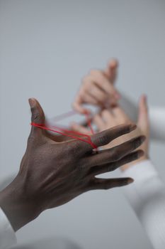 Two hands engage in a classic string game, focusing on connection.