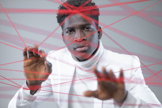 Young man in white creates a striking contrast with red thread in a conceptual studio shoot.