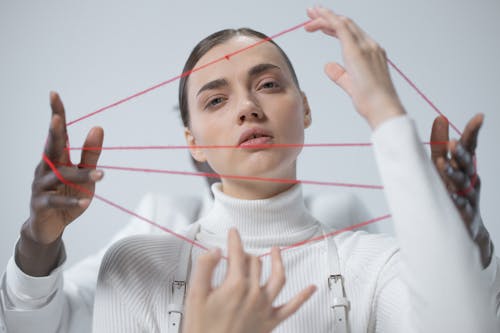 Woman in White Turtleneck Sweater Holding Red Thread