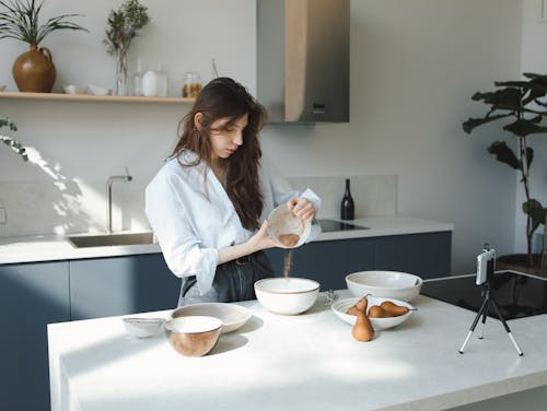 Free Woman in Her White Long Sleeves Preparing a Food on the Kitchen Counter Stock Photo