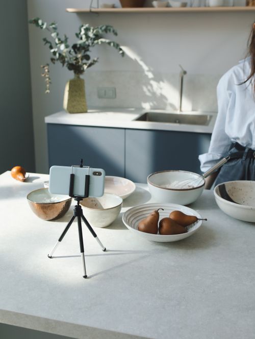 Free A modern kitchen countertop organized with ceramic bowls and a mobile setup for food blogging. Stock Photo