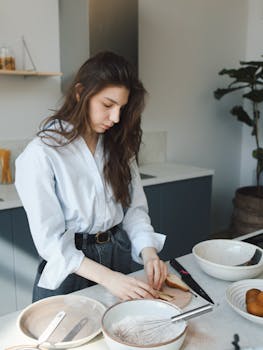 Young woman prepares ingredients in a modern kitchen with a bright and airy atmosphere.