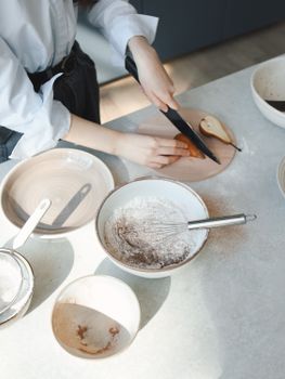 A person slicing pears on a kitchen counter alongside bowls and a whisk.