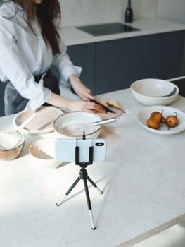 Person recording a cooking session with smartphone and tripod on a kitchen counter.