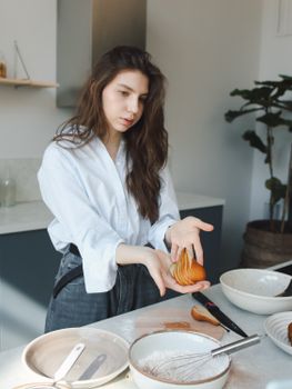A woman prepares a pear tart in a stylish kitchen, showcasing fresh and creative baking techniques.