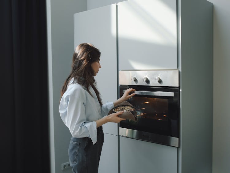 A Woman Cooking Using Oven