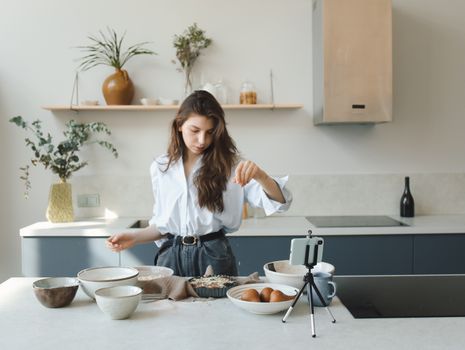 A woman prepares a dish in a modern kitchen, demonstrating culinary skills.