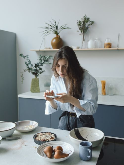 Free Woman photographing dishes in a stylish kitchen, showcasing culinary art. Stock Photo