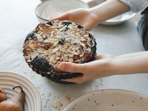Free A homemade pear tart with almond toppings held gently by hands, perfect for food photography. Stock Photo