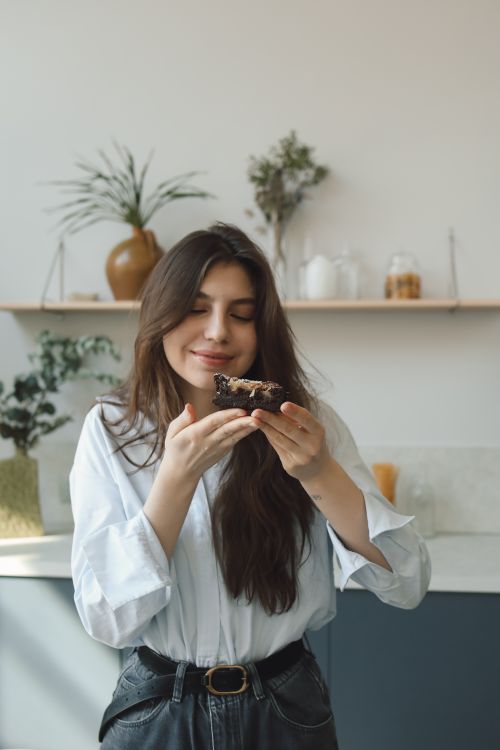 Free Smiling woman savoring a chocolate dessert indoors with natural light. Stock Photo