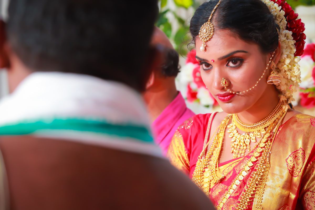 Wedding film still — bride in red silk gazing at the groom