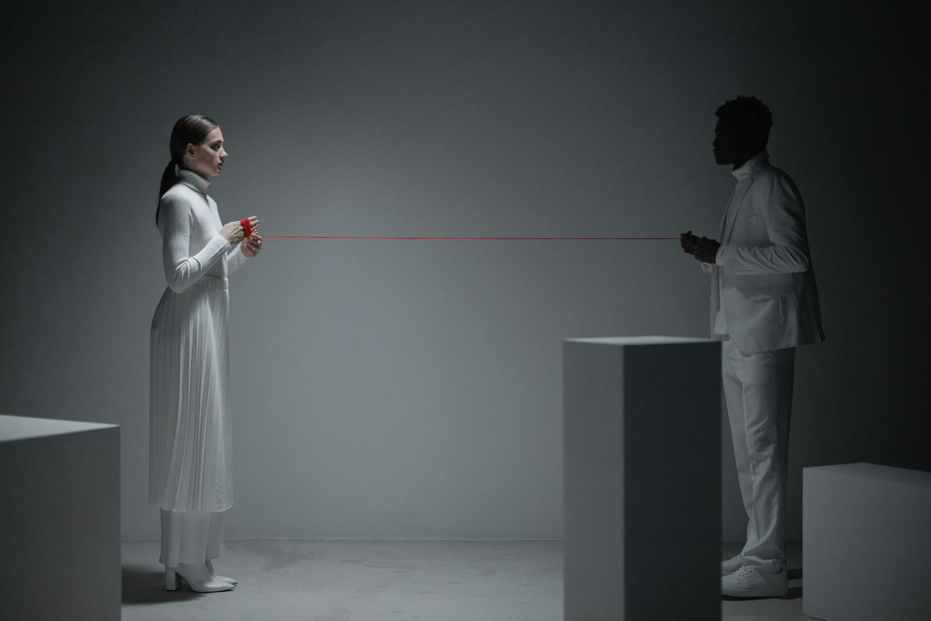 A man and woman symbolically connected by a red thread, representing bond and connection.