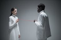 Man and Woman in White Clothes Holding a Red String