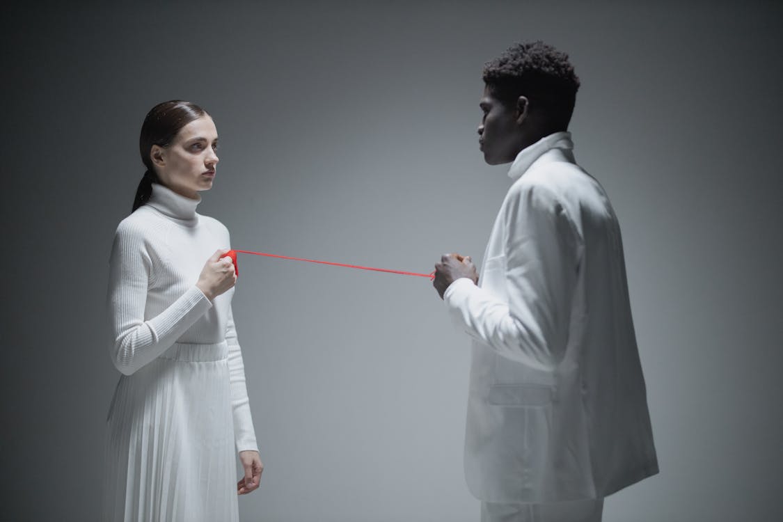 Free Man and Woman in White Clothes Holding a Red String Stock Photo